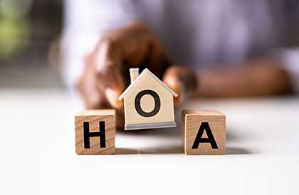Wooden blocks with letters H O A with blurred hand behind